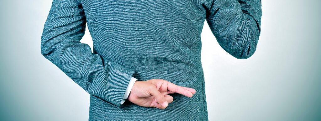 Junger Mann, der einen Eid schwört und hinter seinem Rücken die Finger kreuzt.