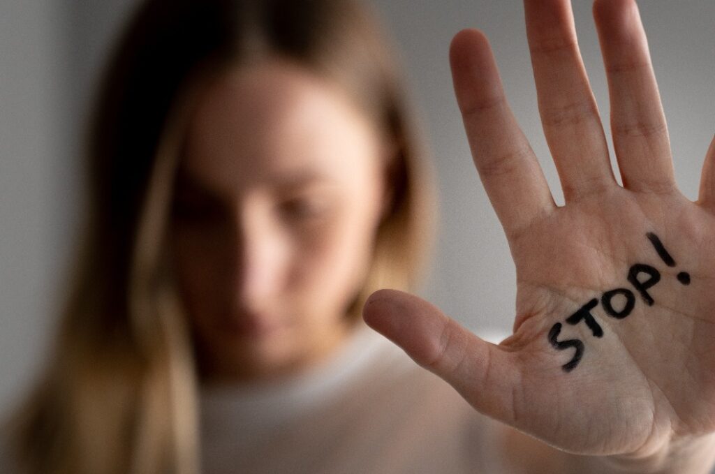 Frau mit blauen Flecken im Gesicht zeigt Stoppschild, Handfläche im Fokus