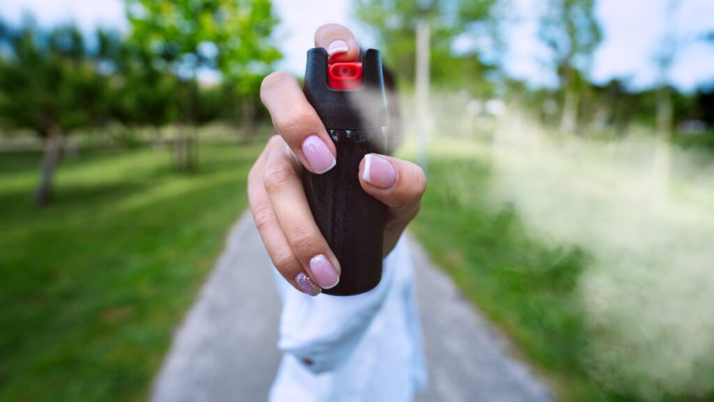 Eine Frau, die im Freien Pfefferspray oder Tränengas zur Selbstverteidigung einsetzt
