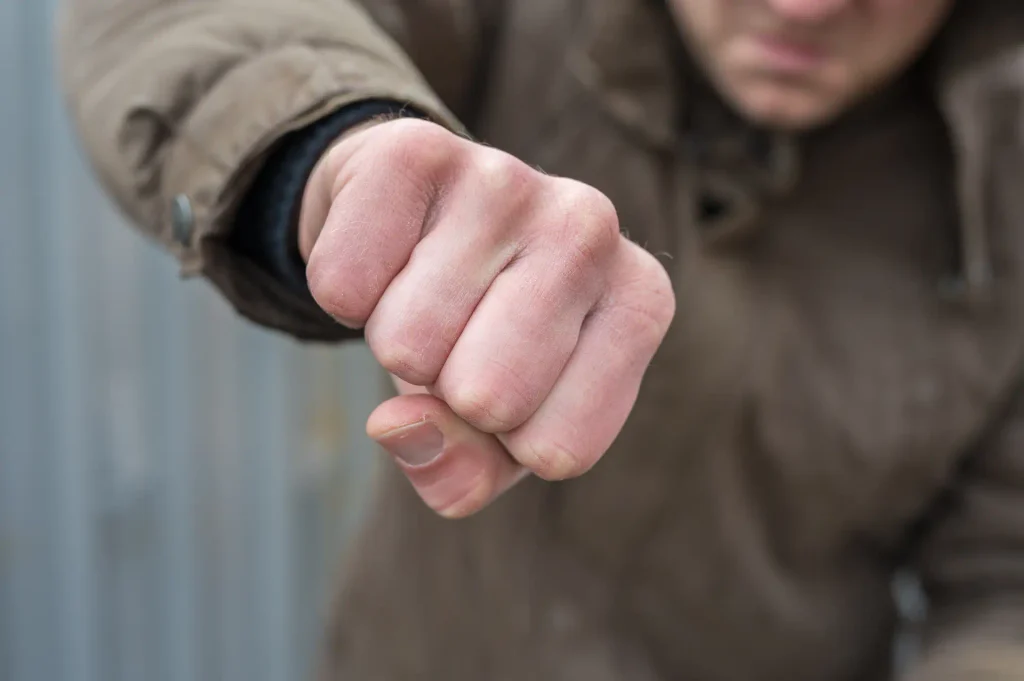 Ein Mann in brauner Jacke streckt aggressiv seine geballte Faust nach vorn